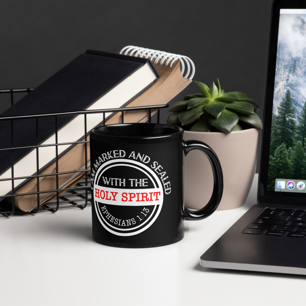 Black Marked and Sealed Holy Spirit mug beside a laptop, books and succulent, handle on right