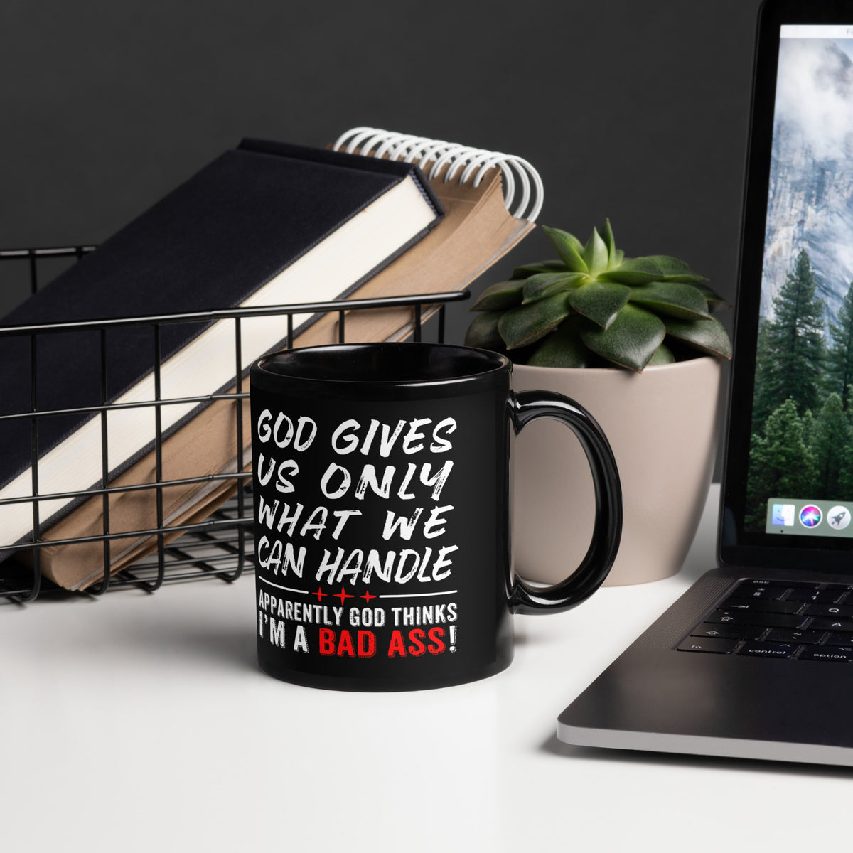 Black faith humor 11 oz mug beside a laptop, notebooks and succulent, handle on right