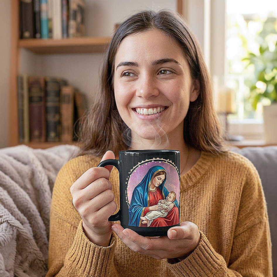 Smiling woman in a mustard sweater holding a steaming black Mary and Jesus mug beside a bookshelf