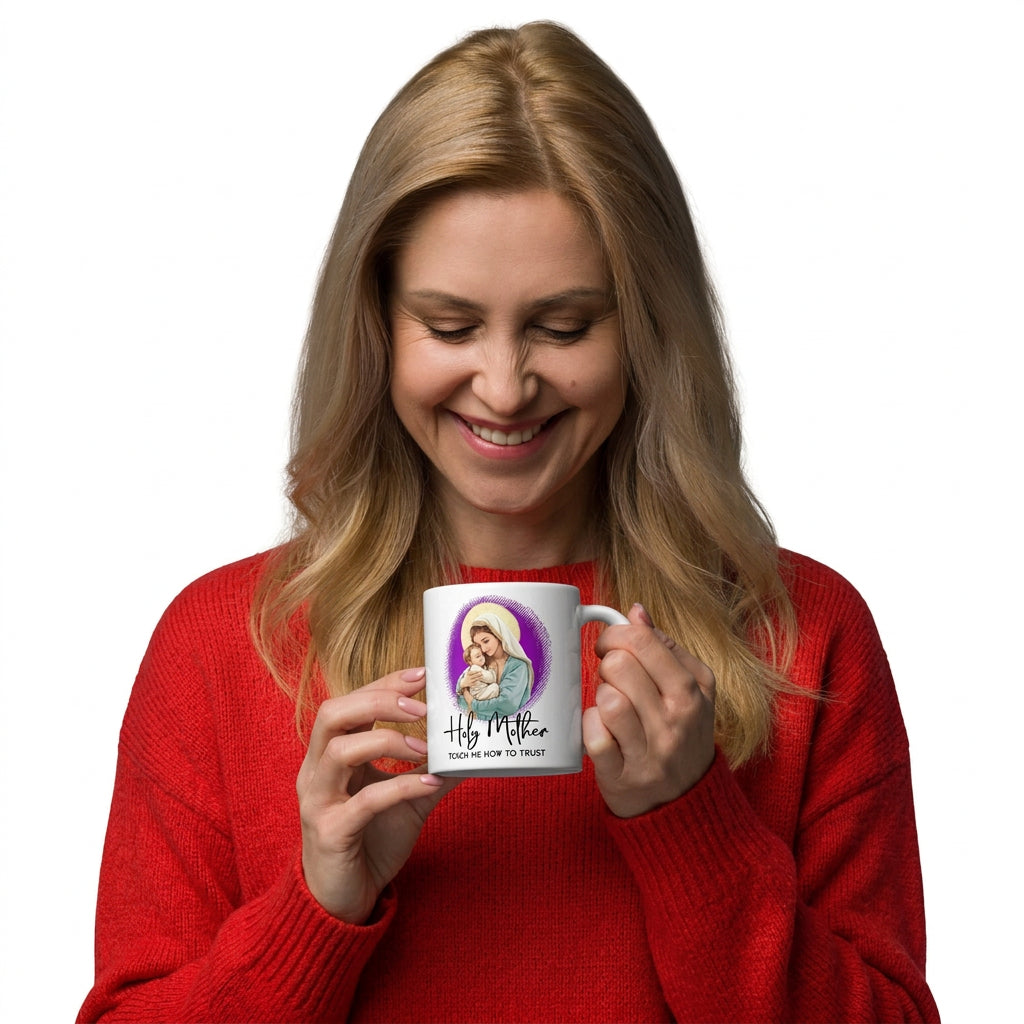 Smiling woman in a red sweater looking down at a white Holy Mother Teach Me How to Trust mug, handle on the right