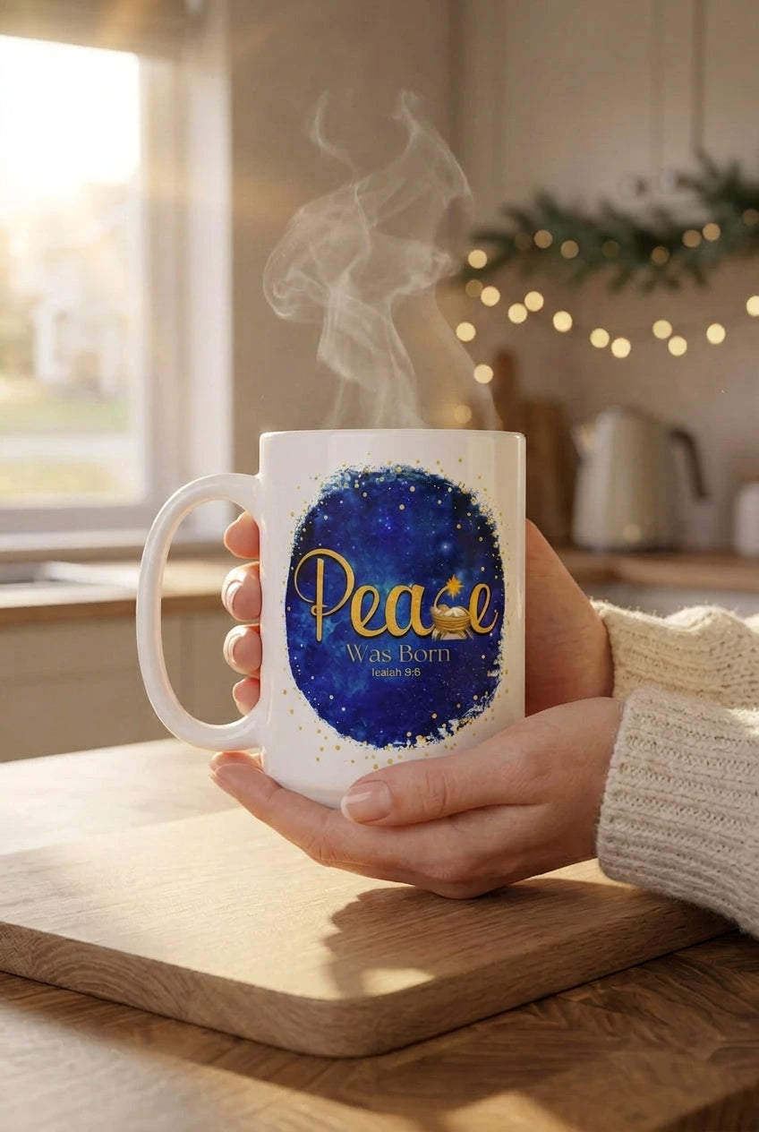 Hands holding a steaming Peace Was Born mug above a wooden board in a kitchen with Christmas greenery, handle on the left