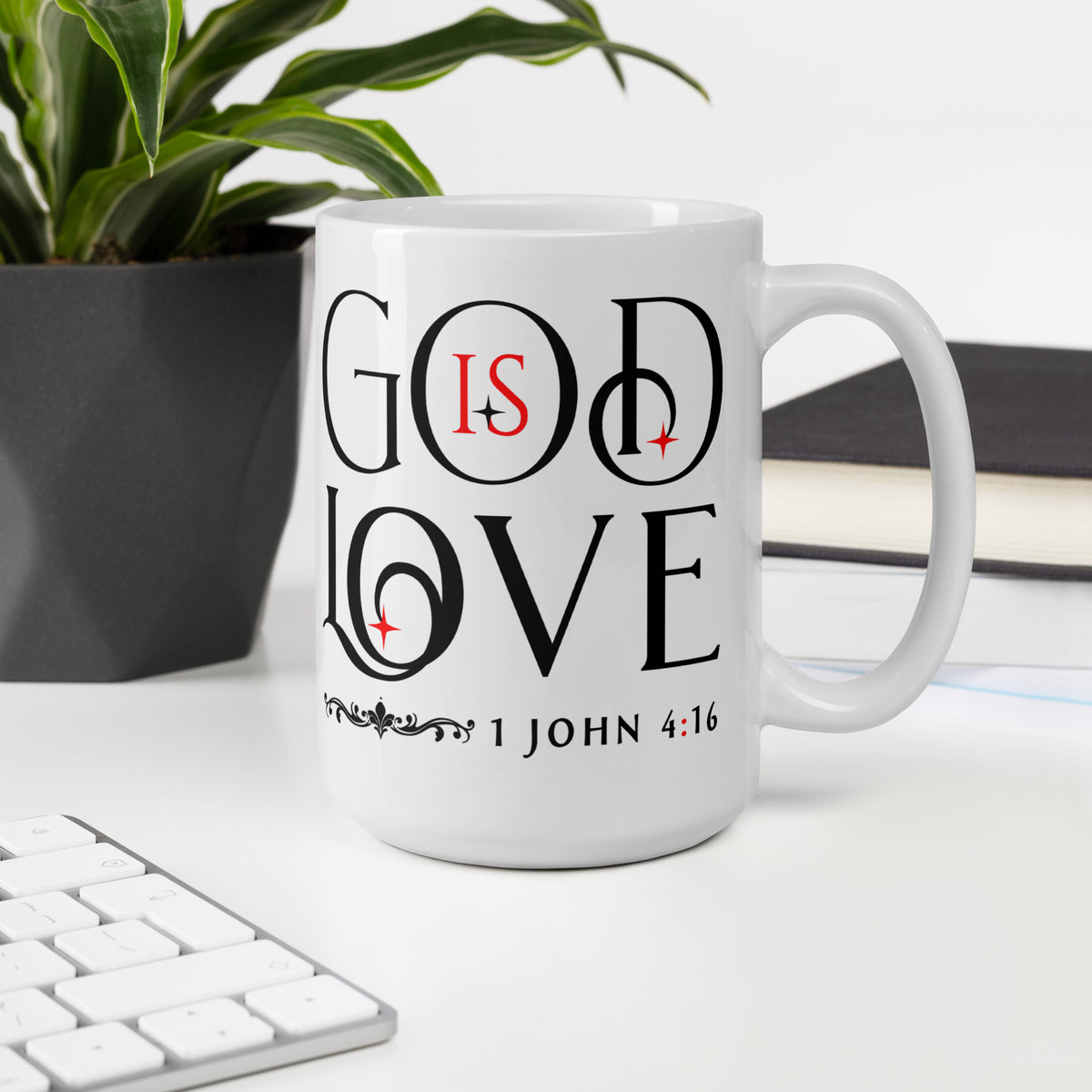 White God Is Love mug on a desk beside a keyboard, plant and notebook, handle on right